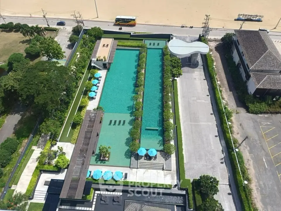 Stunning aerial view of luxury poolside area with lush greenery and beach access.