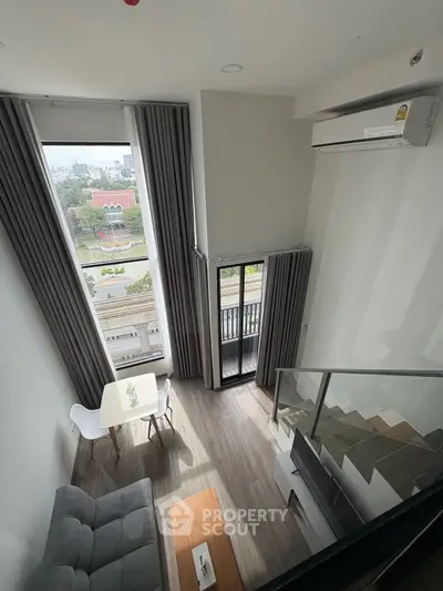 Modern loft apartment with high ceilings and city view from balcony.