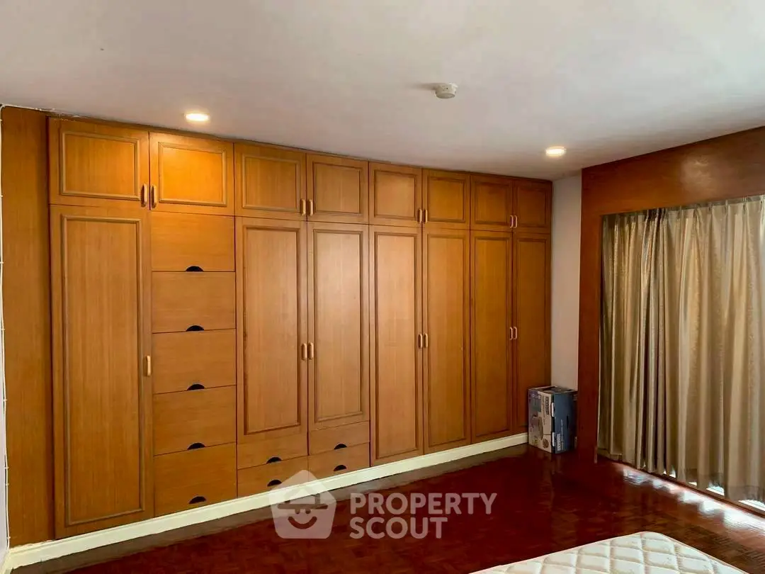 Spacious bedroom with elegant wooden wardrobe and parquet flooring