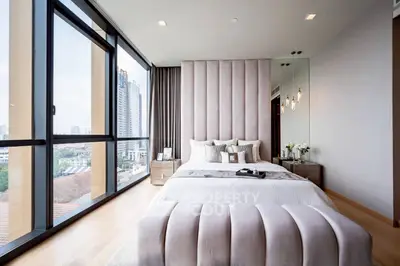 Luxurious bedroom with floor-to-ceiling windows and city view, featuring elegant decor and plush bedding.