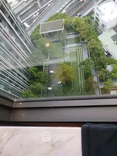 Stunning aerial view from high-rise apartment overlooking lush garden and modern architecture.