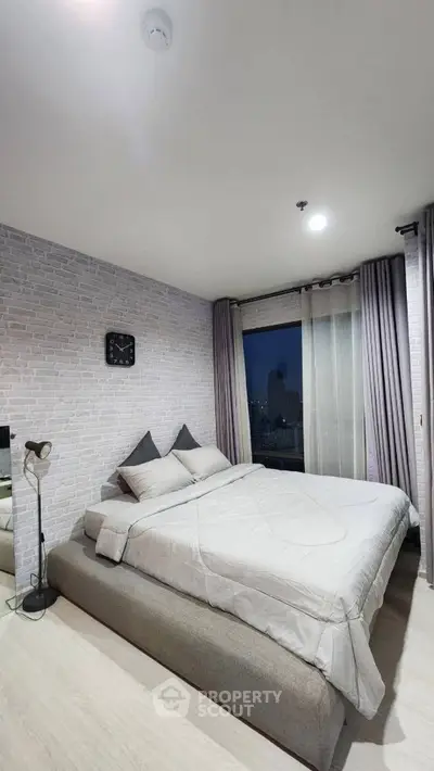 Modern bedroom with stylish decor and city view, featuring a cozy bed and elegant lighting.