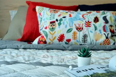 Cozy bedroom with colorful pillows and a small plant on the bed, perfect for relaxation.