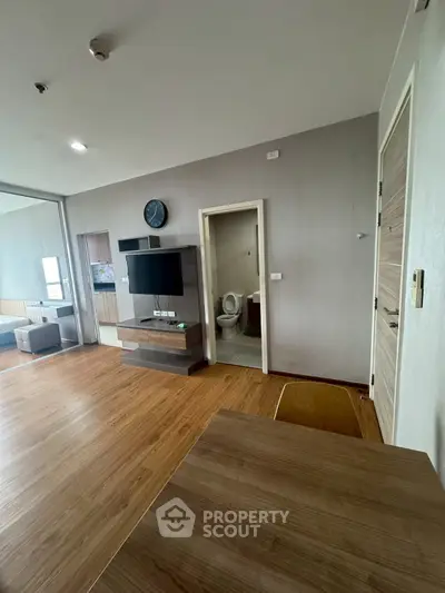 Modern living room with wooden flooring and wall-mounted TV in a stylish apartment.