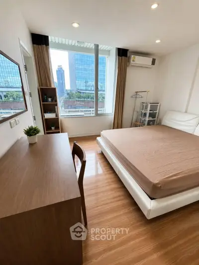 Modern bedroom with city view, featuring sleek furniture and large window for natural light.