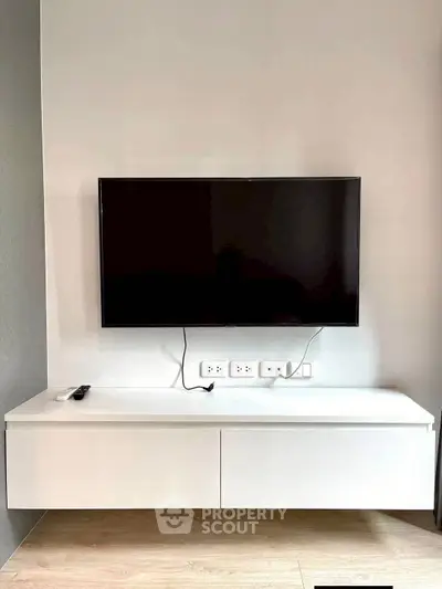Modern living room with wall-mounted TV and sleek white console for minimalist style.