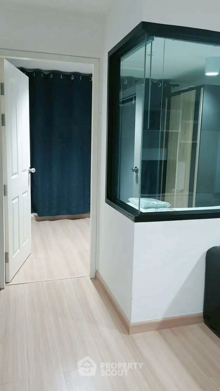 Modern interior with glass partition and wooden flooring, showcasing a sleek and contemporary design.