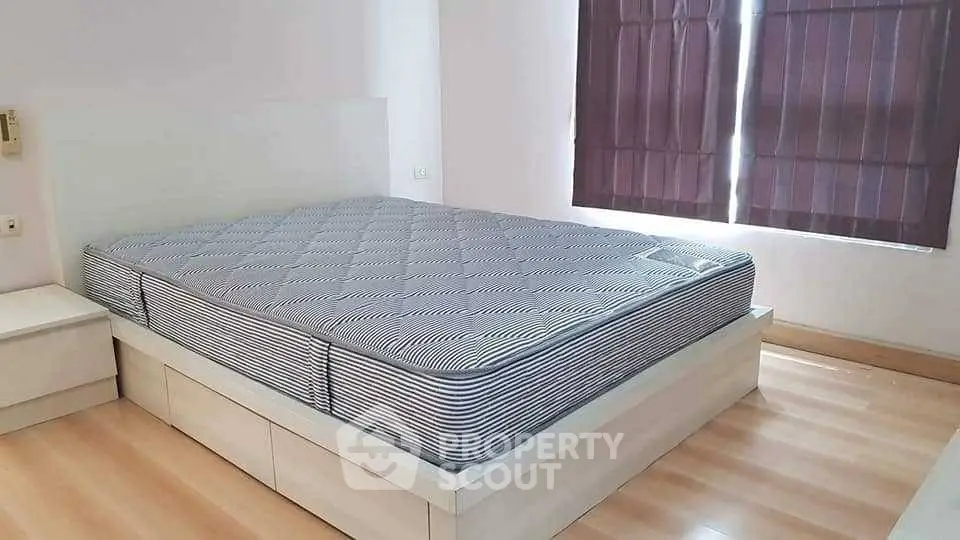 Spacious bedroom with modern bed frame and natural light from window.