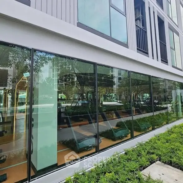 Modern building exterior with large glass windows and lush greenery