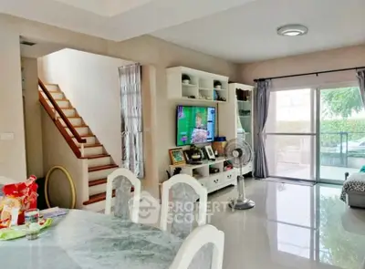 Spacious living room with modern decor and natural light, featuring a dining area and staircase.