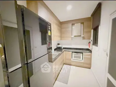 Modern kitchen with sleek appliances and wooden cabinetry in a cozy layout.