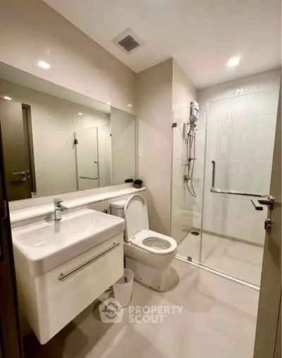 Modern bathroom with sleek fixtures and glass shower enclosure in a contemporary apartment.