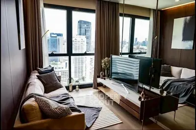Modern living room with city view, cozy sofa, and sleek TV setup.