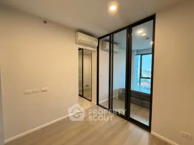 Modern bedroom with mirrored closet and city view in high-rise apartment