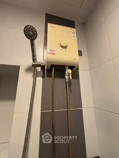 Modern bathroom with shower and water heater in a sleek tiled setting.