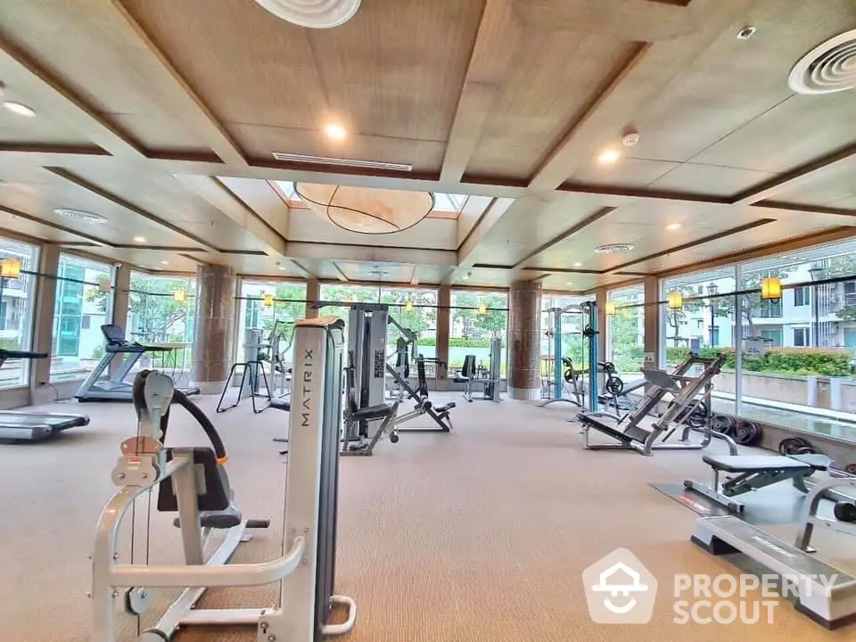 Spacious modern gym with state-of-the-art equipment and large windows offering scenic views.