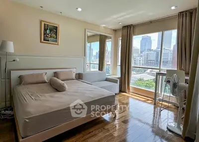 Spacious bedroom with city view, large windows, and modern furnishings in urban apartment.