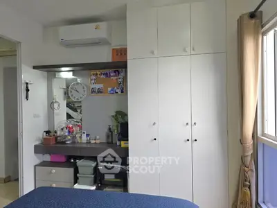 Cozy bedroom with built-in wardrobe and air conditioning, featuring a small workspace and natural light.