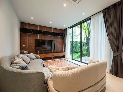 Stylish living room with modern furniture and large glass doors opening to a lush garden view.