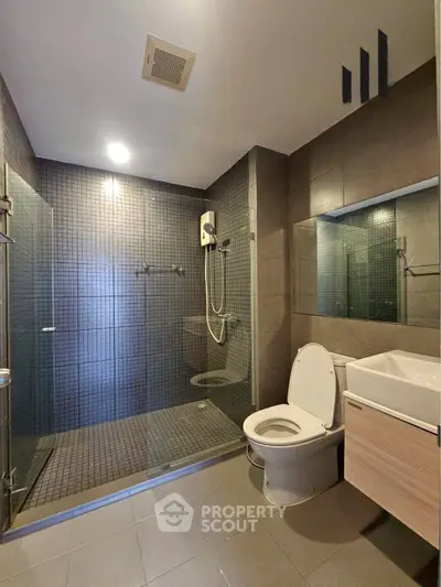 Modern bathroom with glass shower enclosure and sleek fixtures in a contemporary apartment.