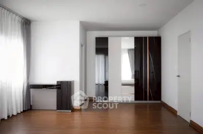 Spacious modern bedroom with sleek wardrobe and elegant wooden flooring.