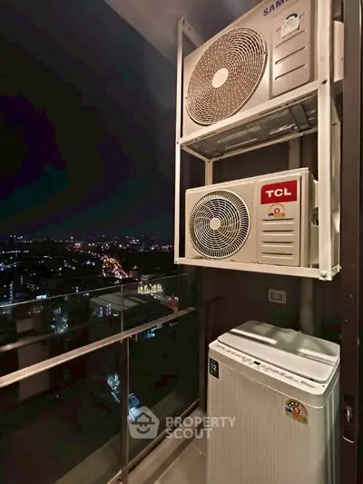 High-rise balcony with city view and air conditioning units at night.