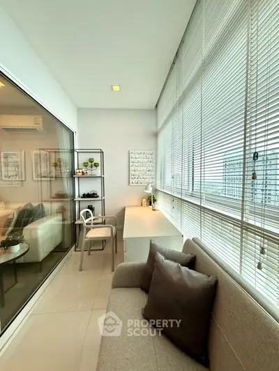 Modern apartment with cozy balcony featuring stylish seating and large windows for natural light.