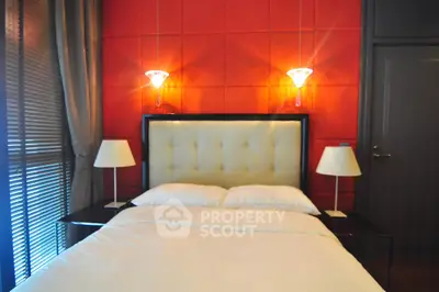 Luxurious bedroom with modern lighting and plush headboard in vibrant red and white decor.