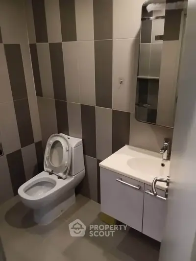 Modern bathroom with sleek design and stylish tiles, featuring a toilet and vanity unit.
