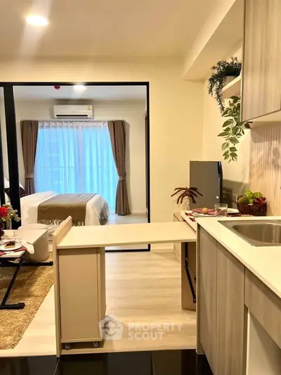 Modern studio apartment with open kitchen and cozy bedroom area, featuring stylish decor and natural light.