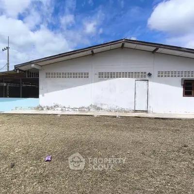 Spacious single-story building with large yard under a clear blue sky, ideal for development.