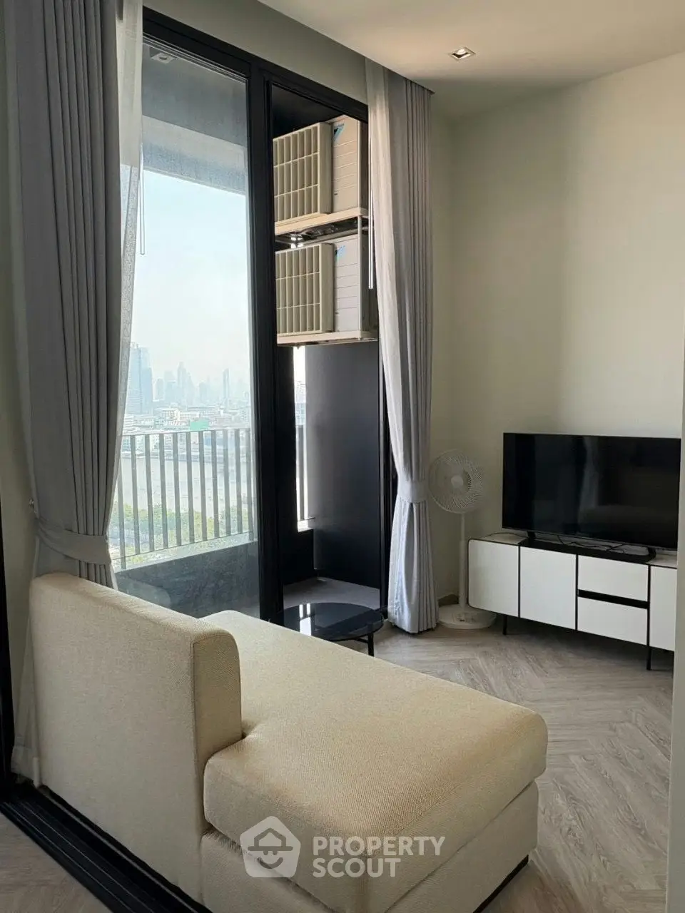 Modern living room with city view, featuring a cozy sofa, sleek TV stand, and large windows for natural light.