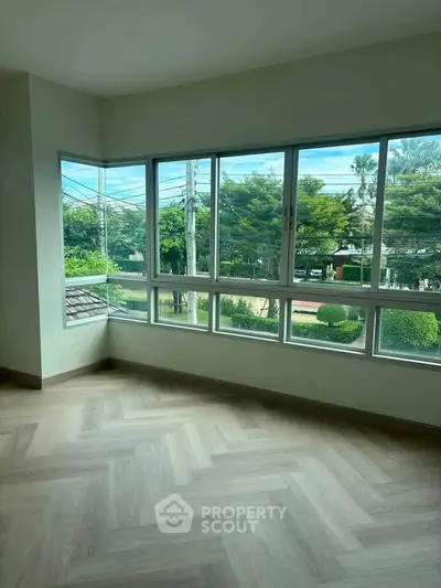 Bright corner unit with large windows offering a stunning view of lush greenery, perfect for a serene living space.