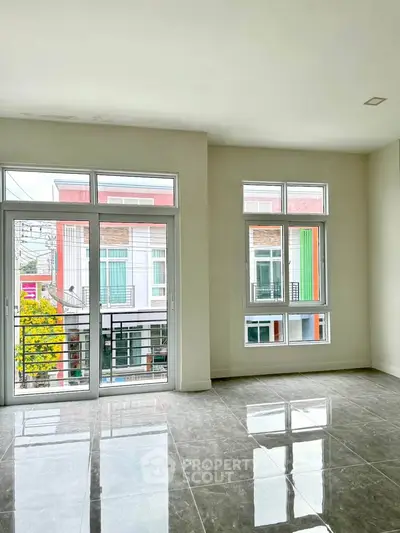 Spacious modern living room with large windows and glossy tiled floor, offering a bright and airy ambiance.