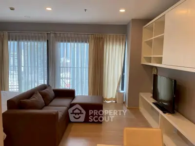 Modern living room with large windows and stylish furniture in a high-rise apartment.