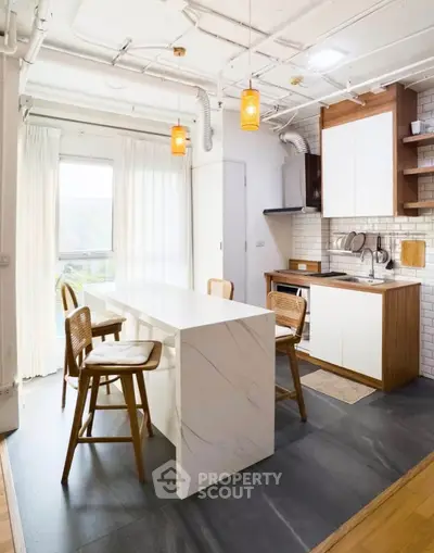Modern kitchen with sleek island and stylish lighting, featuring open layout and natural light.