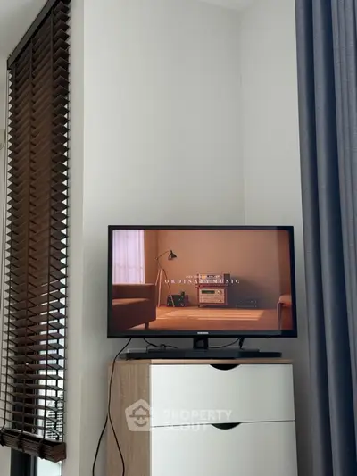 Modern living room with TV on wooden cabinet and stylish blinds.