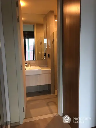 Modern bathroom with sleek design, featuring a glass shower enclosure and a stylish vanity sink, complemented by warm lighting and a large mirror.