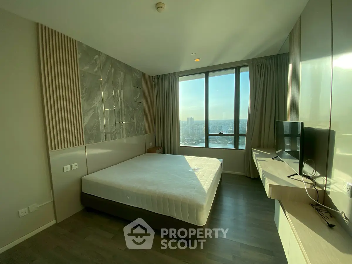 Modern bedroom with large window offering stunning city view and sleek furnishings.