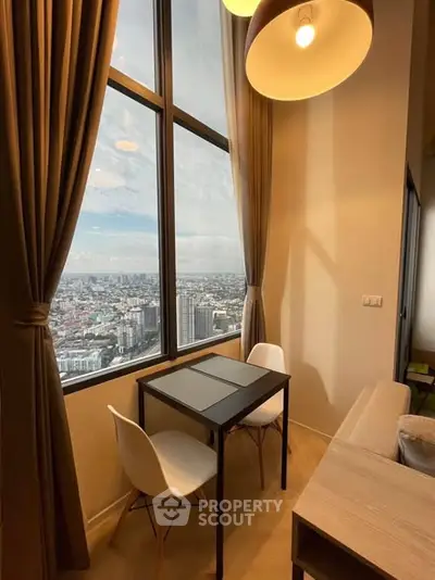 Stunning high-rise apartment with panoramic city view and cozy dining area.