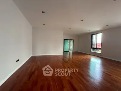 Spacious empty living room with hardwood floors and large windows.