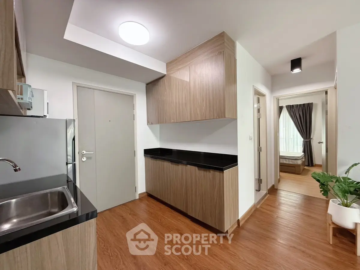 Modern kitchen with sleek wooden cabinets and black countertops in a stylish apartment.