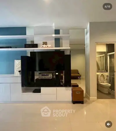 Modern living room with sleek entertainment center and glimpse of bathroom