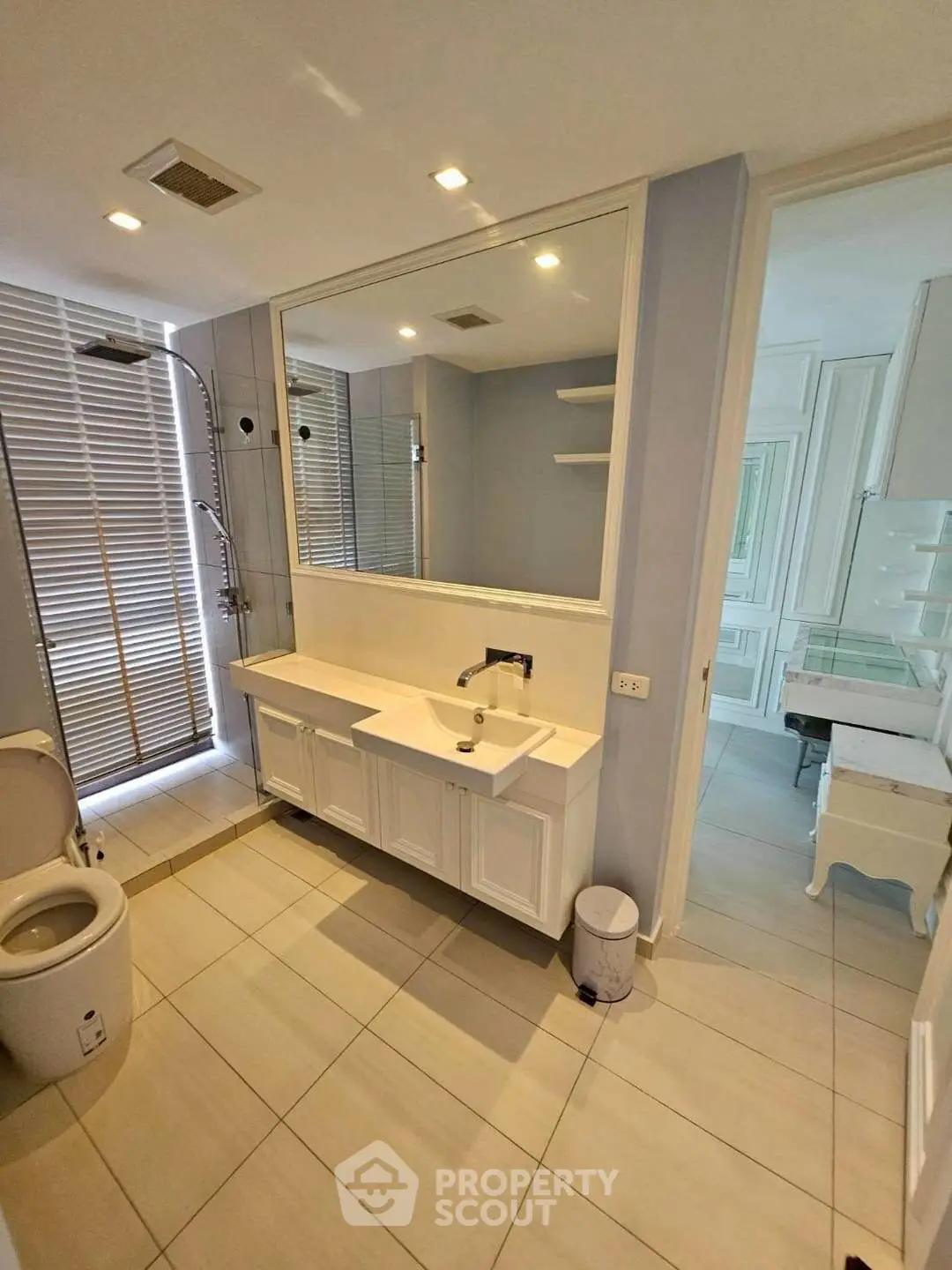 Elegant bathroom with modern fixtures and large mirror, featuring a spacious shower and stylish vanity.