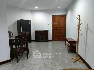 Spacious living area with dining set and modern refrigerator, perfect for comfortable living.