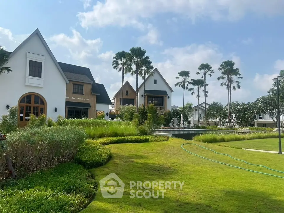 Charming residential community with lush gardens and modern houses under a clear blue sky.