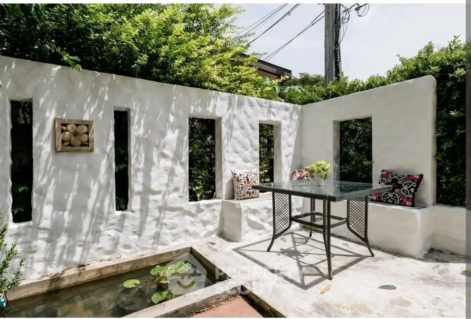 Charming garden patio with stylish seating and decorative pond, perfect for relaxation.
