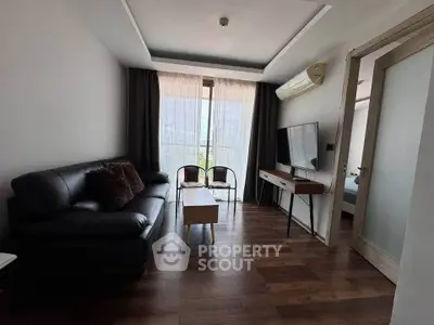 Modern living room with sleek furniture and large window, featuring a cozy black sofa and stylish wooden flooring.