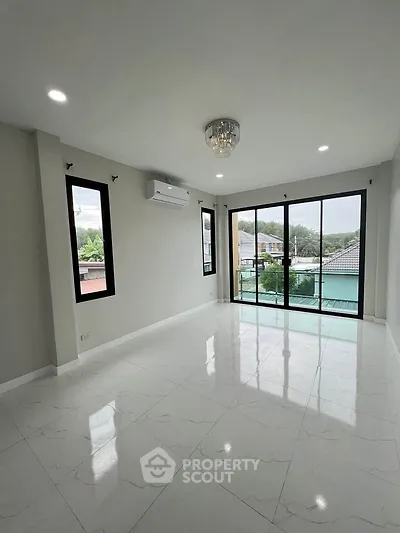 Spacious living room with large windows and balcony offering natural light and scenic views.