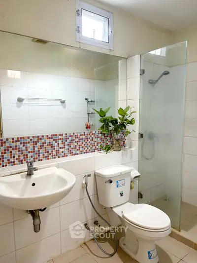 Charming bathroom with modern fixtures and colorful mosaic tile accents.